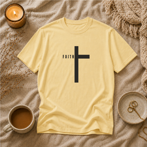 Yellow t-shirt with a black cross and 'FAITH' text on a textured surface with a candle and cup.