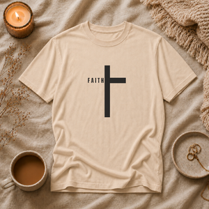 Beige t-shirt with a black cross and 'FAITH' text on a textured surface with a candle and cup.